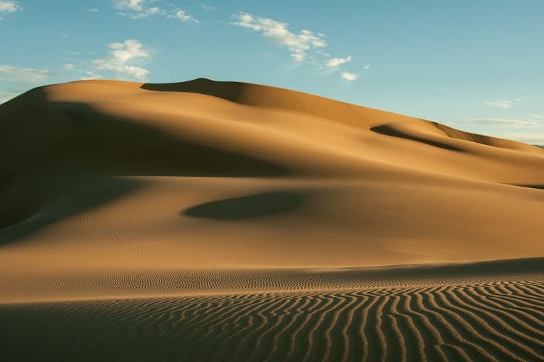 A stunning image of vast sand dunes under a clear blue sky, showcasing the beauty of the desert landscape.