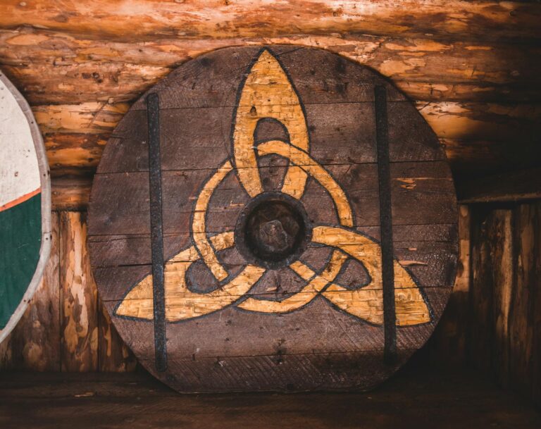 Aged wooden Viking shield decorated with ornament placed on lumber shelf in traditional museum in Norstead village