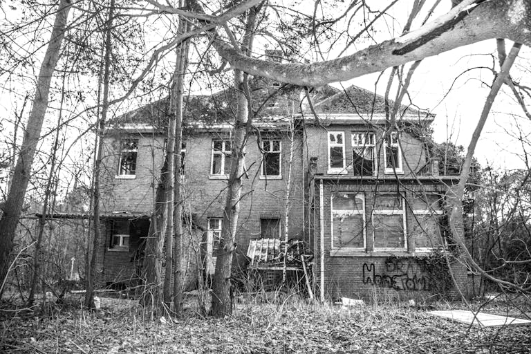 Eerie black-and-white photo of an abandoned house with a haunted atmosphere.