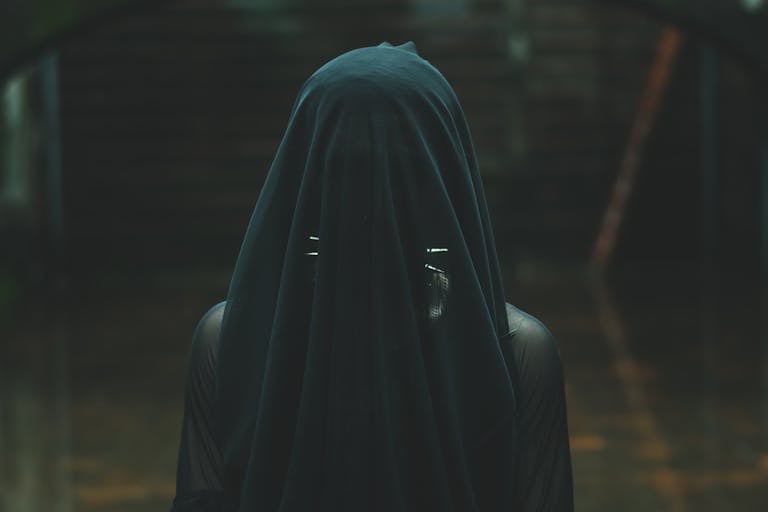 Intriguing image of a person draped in a dark veil, evoking mystery and fashion.