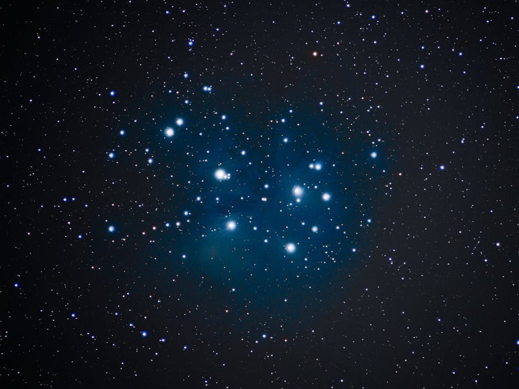 The Pleiades star cluster, also known as the Seven Sisters, glowing brightly in the night sky.