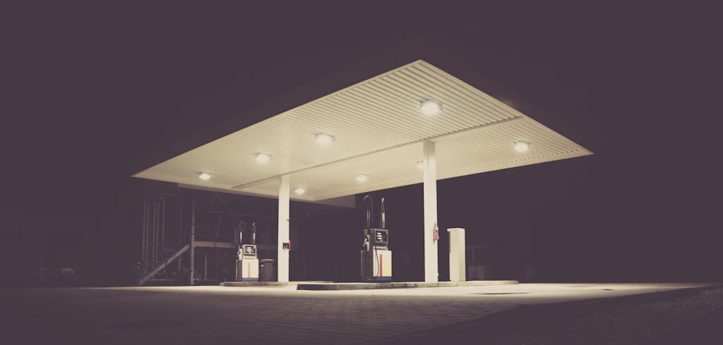 A dimly lit gas station at night, offering an eerie and calm atmosphere with dark surroundings.