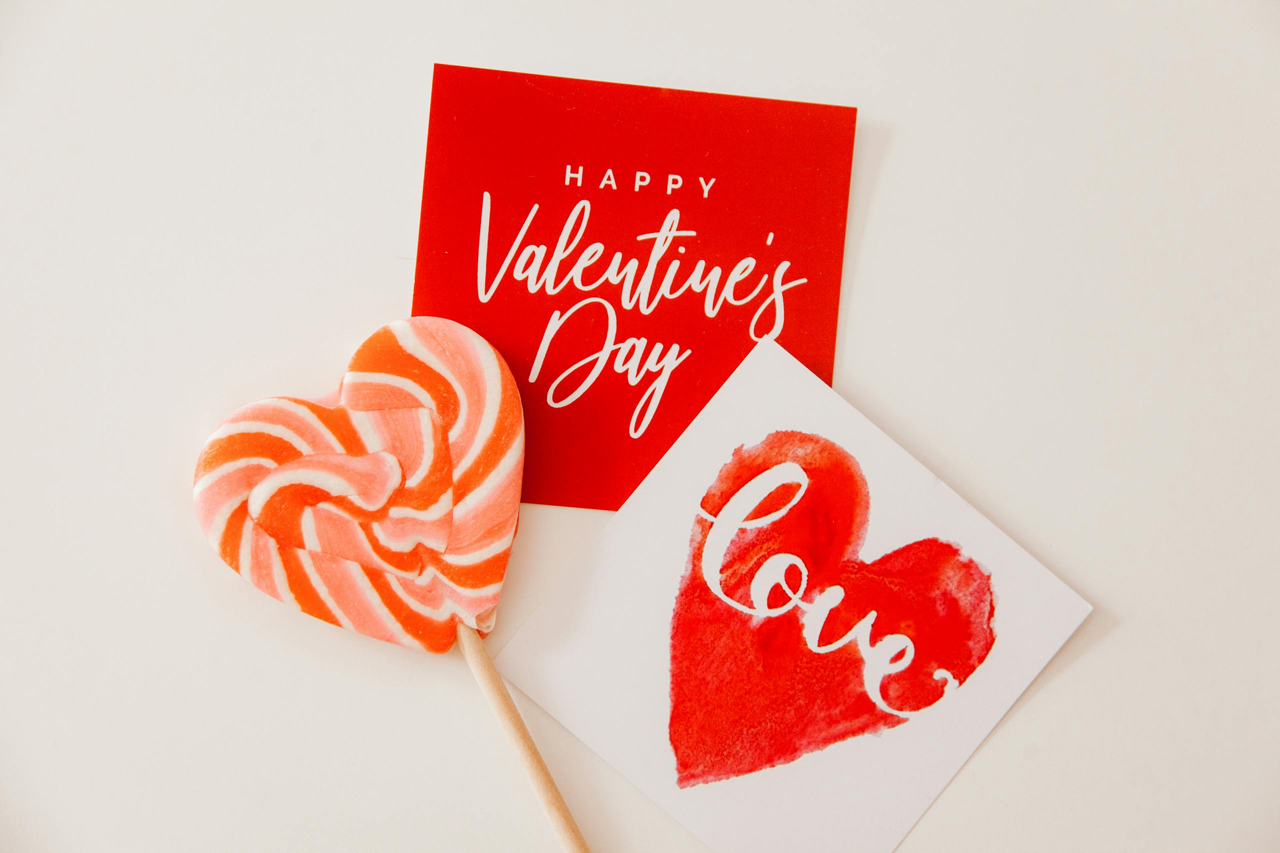 Heart-shaped lollipop and Valentine's Day cards in a flatlay for love theme.