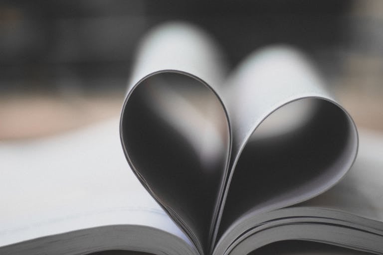 Open book pages forming a heart shape, symbolizing love and creativity.